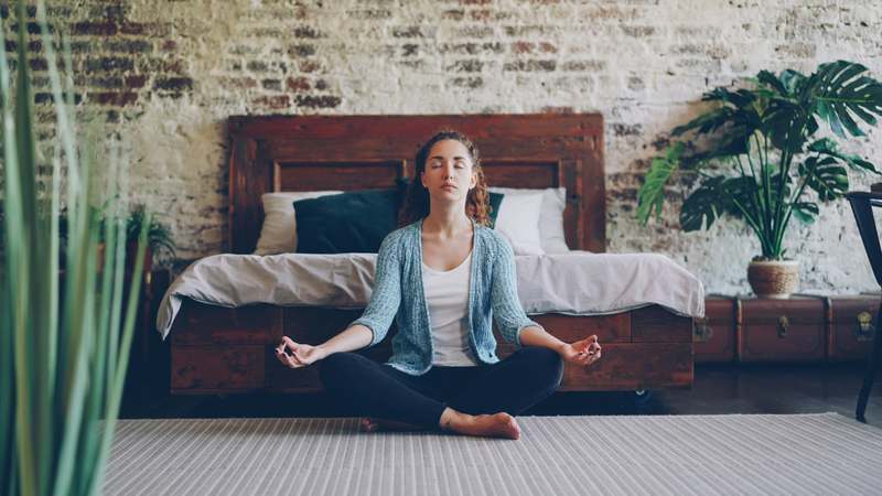 Woman sitting peacefully in natural light, holding a cup of herbal tea and journaling beside fresh lavender and leafy greens — representing calm, hormonal wellness, and daily self-care rituals